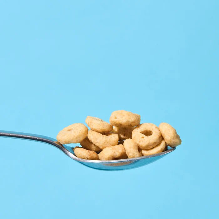 Close-up of a spoon holding Yo Keto Protein Cereal - Cinnamon Flavour - 250g by Low Carb Emporium on a blue background