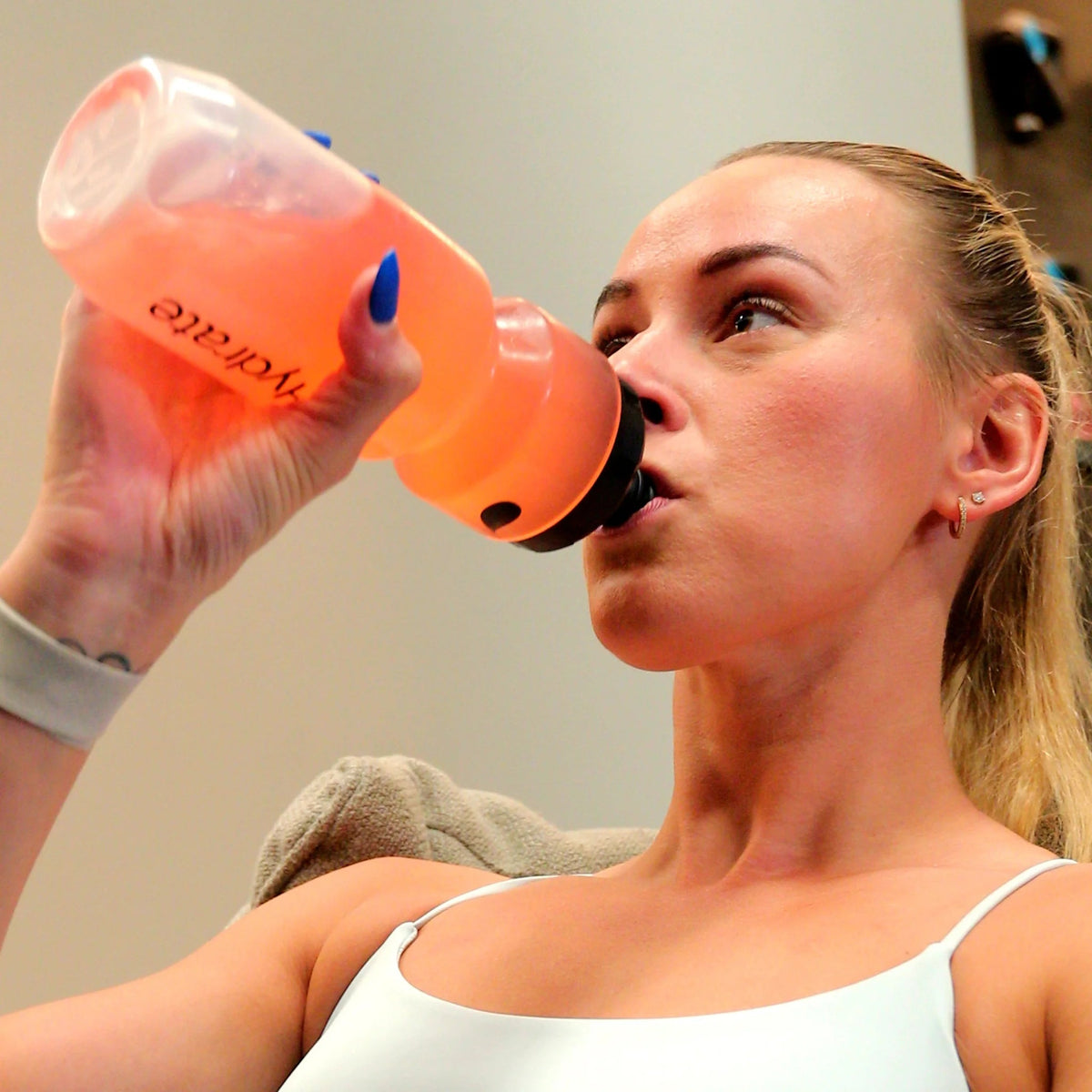 Woman drinking from Dr. Hydrate bottle with Strawberry Kiwi Jar - 30 Serves in a fitness setting, promoting hydration.